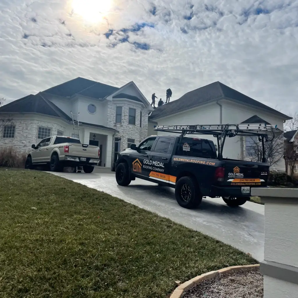 A two story roof being inspected by gold medal roofing contractors while their company truck is parked in front of the house. The sky is cloudy and rain looks to be approaching.