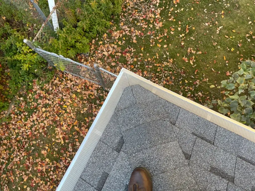 Aerial view of a newly installed gutter system on a residential roof, showcasing the seamless integration of the gutter with the roof's edge. The gutter is made of durable material and features a sleek design, blending in with the surrounding architecture. A gutter contractor's expertise is evident in the precise installation, ensuring a watertight seal and efficient water flow. The image highlights the importance of a well-functioning gutter system in protecting the home from water damage and maintaining its structural integrity.