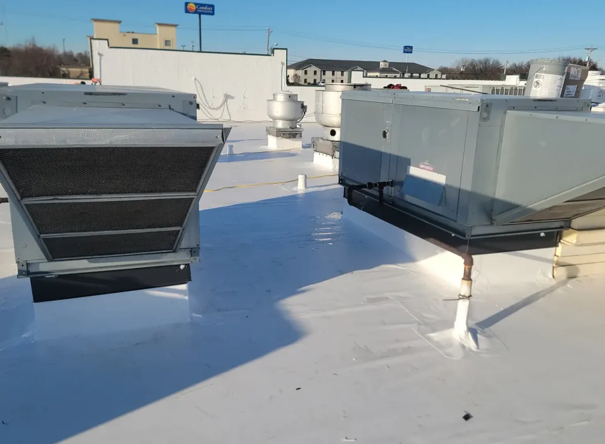 Flat roofing installation on a commercial building, featuring a white, seamless membrane with a smooth finish, providing a durable and waterproof surface, with HVAC units and other equipment visible, highlighting the importance of a reliable and long-lasting roofing system for commercial properties.