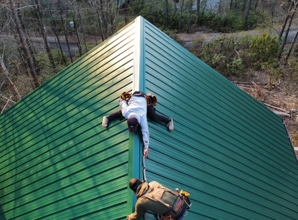 Crew members at work, installing sleek green metal roofing.